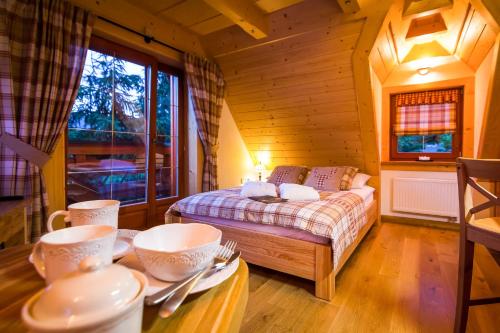 a room with a bed and a table with cups and plates at Rezydencja Na Szymoszkowej in Zakopane
