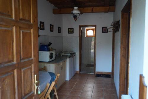 a room with a kitchen with a door and a microwave at Cseresznyés Vendégház in Szomolya