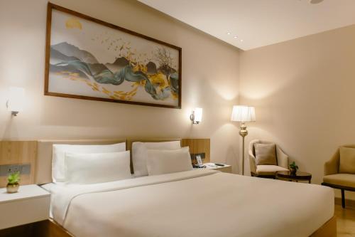 a bedroom with a large white bed and a chair at Udman Hotel Gurugram in Gurgaon