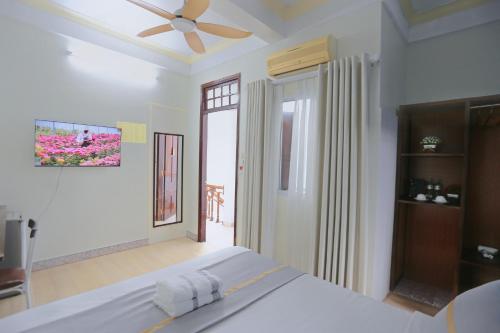 a white bedroom with a bed and a ceiling fan at Hue Imperial Hostel in Hue