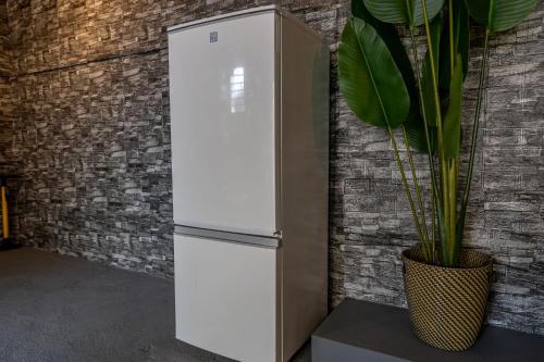 a white refrigerator against a brick wall with a plant at Lax奈良 奈良観光に便利な和モダン古民家 最大12名 グループや家族旅行に最適 in Nara