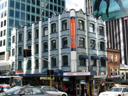 a large white building on a city street with cars at Surf 'N' Snow Backpackers Across Sky Tower in Auckland