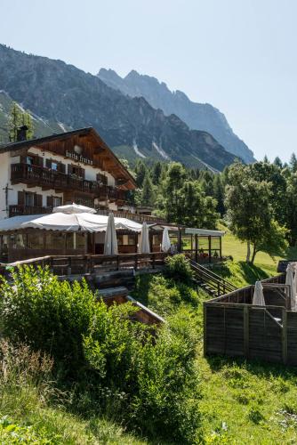 a building with tables and umbrellas in a field at Baita Fraina in Cortina dʼAmpezzo