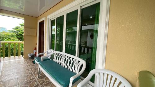 a porch with two white benches on a balcony at HMC Guesthouse - Malapascua Island Air-conditioned Room #2 in Logon