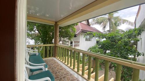 a balcony with two chairs and a view of a house at HMC Guesthouse - Malapascua Island Air-conditioned Room #2 in Logon
