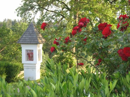 a white bird house in a garden with red roses at Biogasthaus Wanker in Techelsberg am Worthersee