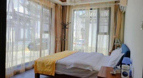 a bedroom with a bed and a large window at Dali Four Seasons Hostel in Dali Ancient Town