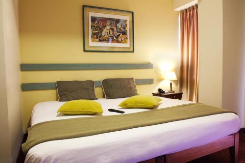 a bedroom with a large bed with yellow pillows at Kamana Hotel in Lima