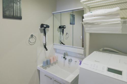 a white bathroom with a sink and a mirror at 森の晴 in Osaka