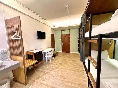 a room with two bunk beds and a desk and a table at Need a Nap Hostel Phrae in Phrae