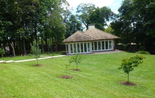 two trees in the grass in front of a building at Quiosque Golf Santa Cruz do Sul in Santa Cruz do Sul