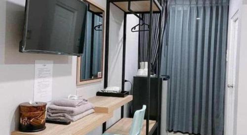 a bathroom with a flat screen tv and towels at The Hub Hotel Surin in Surin
