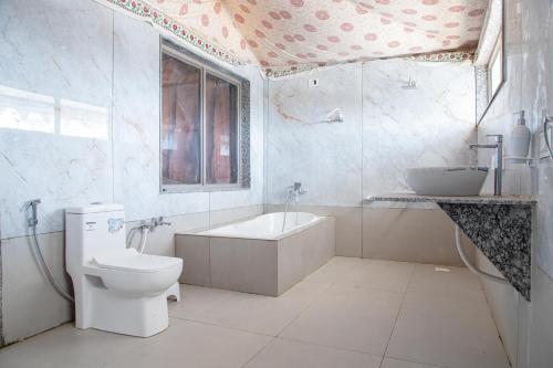 a bathroom with a toilet and a tub and a sink at Stayguru Road to Heaven Resort in Kunria