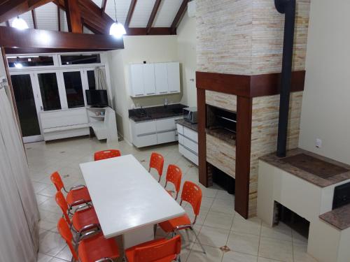 a kitchen with a white table and orange chairs at Quiosque Golf Santa Cruz do Sul in Santa Cruz do Sul