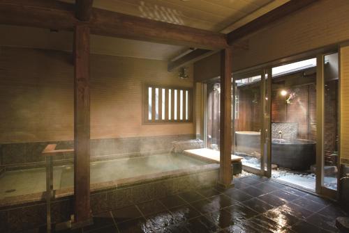 a bathroom with a bath tub and a bath tub at Ryokan Tanabe in Takayama