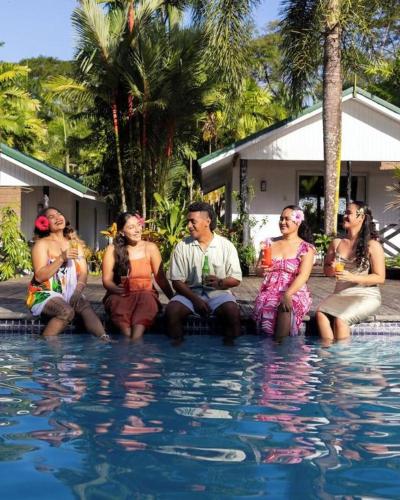 a group of people sitting around a swimming pool at Orator Hotel in Apia