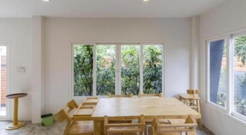 a dining room with a table and some windows at Maximize Brand New Hostel Udonthani in Udon Thani