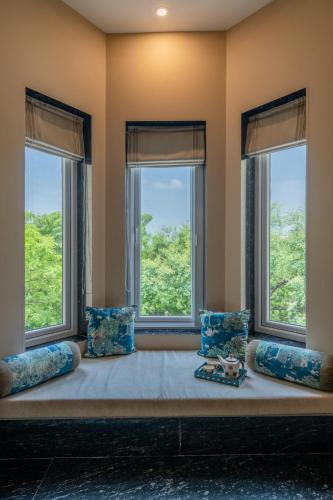 a large bed in a room with three windows at Umaid Palace - A Lakeside Resort - 25 minutes from Mehandipur Balaji - 20 minutes from Chand Baori Stepwell Abhaneri & 40 minutes from Bhangarh Fort in Dubbī