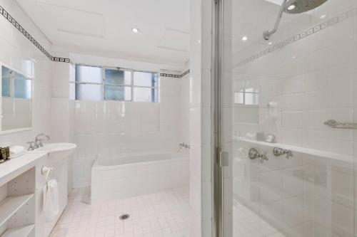 a white bathroom with a shower and a tub at Castlereagh Boutique Hotel, an Ascend Collection Hotel in Sydney