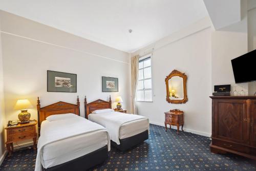 a hotel room with two beds and a mirror at Castlereagh Boutique Hotel, an Ascend Collection Hotel in Sydney