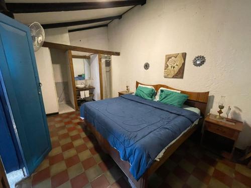 1 dormitorio con 1 cama con sábanas azules y almohadas verdes en Hostal Casona de los Vega, en Izalco