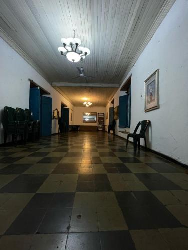 Un salón vacío con suelo a cuadros y sillas. en Hostal Casona de los Vega, en Izalco