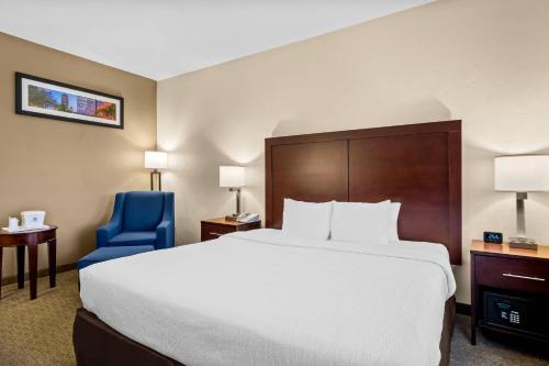 アービングにあるQuality Suites Irving-Las Colinasの大きなベッドと青い椅子が備わるホテルルームです。