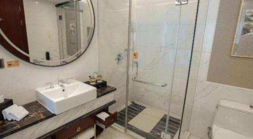 a bathroom with a sink and a shower with a mirror at Zhangjiagang Zhonglian GDH International Hotel in Zhangjiagang