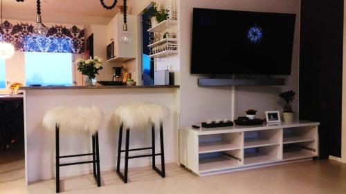 a living room with two white furry stools and a tv at Vasko Luxurious Suites, Firefox in Rovaniemi