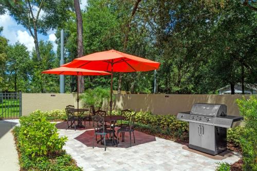 a grill and tables and chairs with an umbrella at MainStay Suites Orlando Altamonte Springs in Orlando