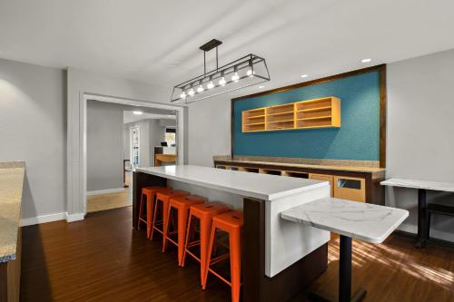 a kitchen with a white counter and orange stools at MainStay Suites Salt Lake City Fort Union in Midvale