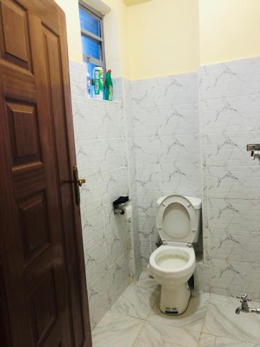 a white bathroom with a toilet and a window at The hideout in Ruiru