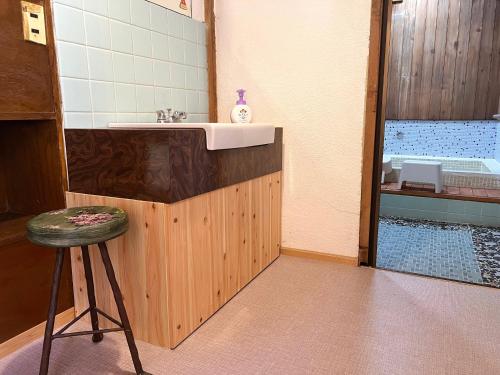 a bathroom with a sink and a stool next to a shower at Yado Nishimura Timeless Japan Experience in Shizuoka