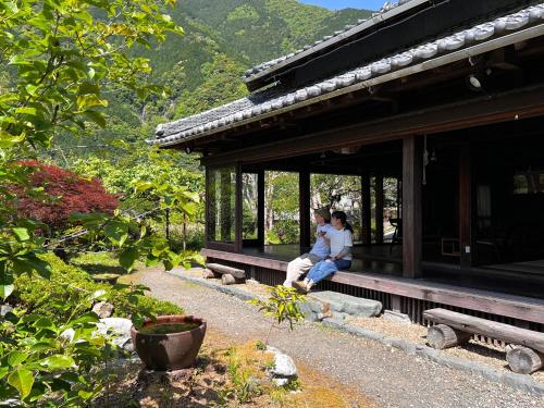 two people sitting on a porch of a building at Yado Nishimura Timeless Japan Experience in Shizuoka