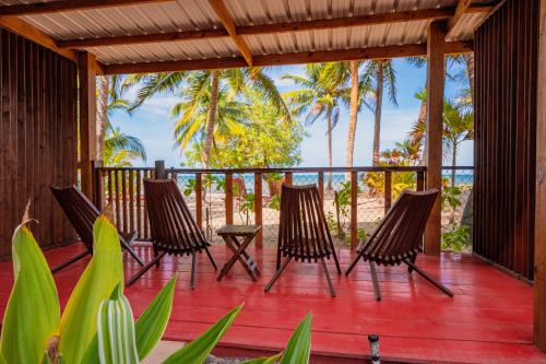 a deck with four chairs and a table on the beach at Buttonwood Belize in Hopkins