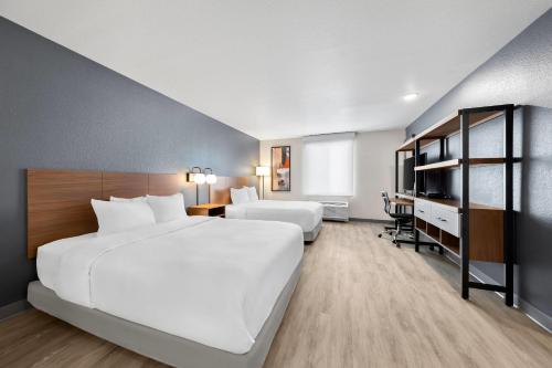 Una habitación de hotel con dos camas y un escritorio. en Everhome Suites San Bernardino - Loma Linda, en San Bernardino