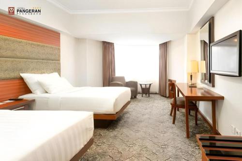 a hotel room with two beds and a desk at Hotel Pangeran in Pekanbaru