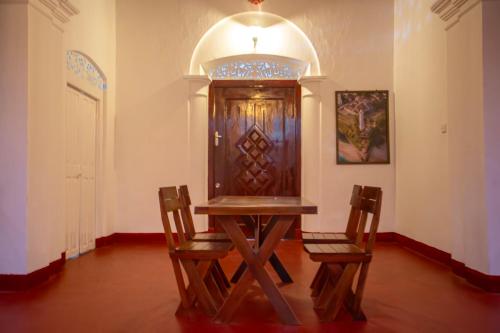 a table and two chairs in a room with a door at Villa De Sal in Galle
