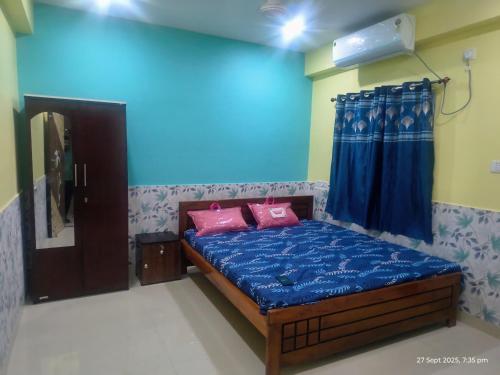 a bedroom with a bed with blue sheets and pink pillows at New Projapati Guest House, Prantik Road in Shānti Niketan
