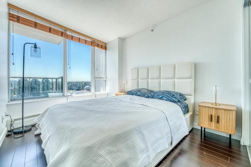 ein Schlafzimmer mit einem großen Bett und einem großen Fenster in der Unterkunft Central City Location, Bay View, One Free Parking in Vancouver