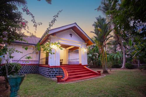 a small house with a red staircase in the yard at Villa De Sal in Galle