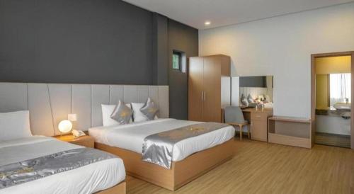 a hotel room with two beds and a desk at Gold View Boutique Hotel Đà Lạt in Da Lat