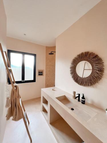 ein Badezimmer mit Waschbecken und Spiegel an der Wand in der Unterkunft BAYA - Modern & Cozy 2BR Villa Uluwatu in Bingin Beach