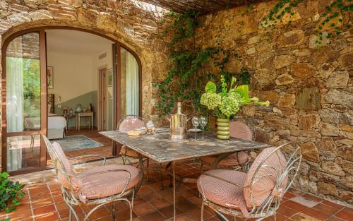 a dining room with a table and chairs and a stone wall at Domaine Les Mésanges in Saint-Tropez