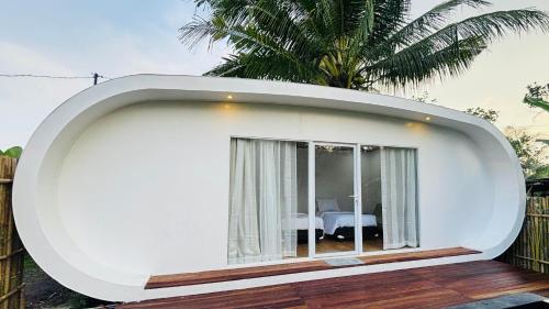 a round house with a window on a deck at Nira Meraki Divasha in Bedoyo