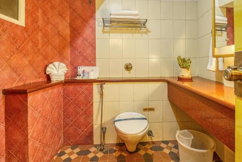 a bathroom with a toilet and a sink in it at Parklane Hotel in Mysore