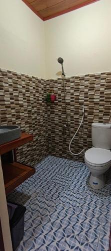 a bathroom with a toilet with a shower at marvin's guesthouse in Lovina
