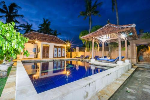 a villa with a swimming pool at night at Pondok Baruna Garden in Nusa Lembongan