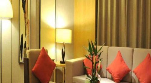 a living room with a white couch with red pillows at Ramada by Wyndham Zhengzhou East in Zhengzhou