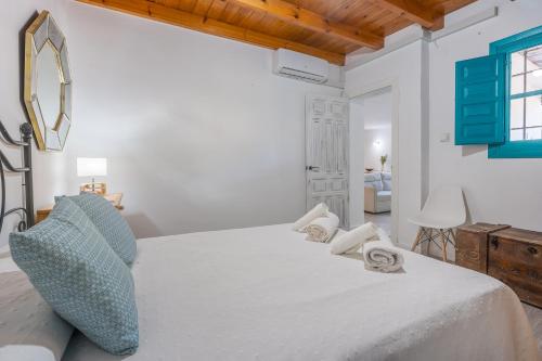 a white bedroom with a large bed with towels on it at Casa adelfas in Granada